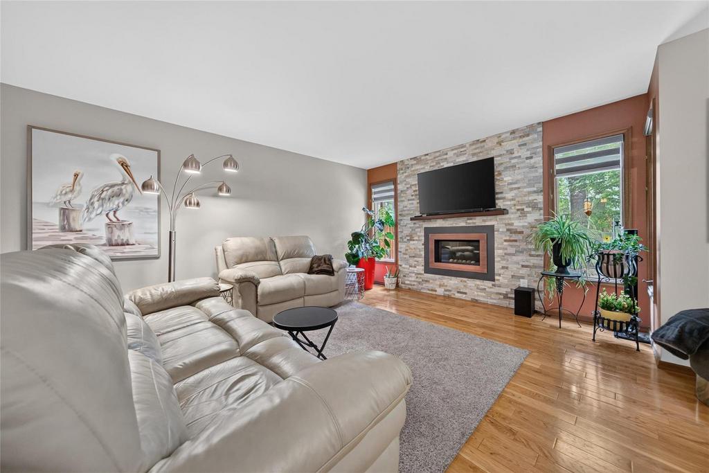 Open-concept living and dining room with gas fireplace and stone feature wall